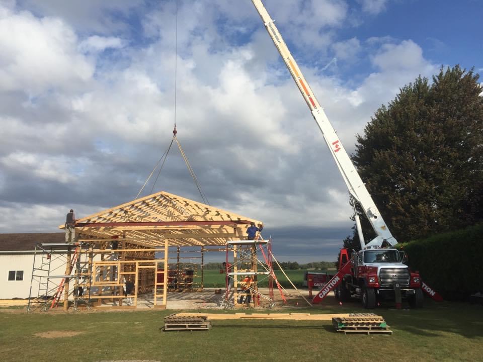 A crane is lifting up the roof of a building.