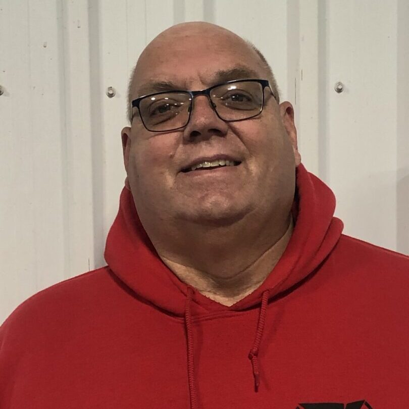 A man in red hoodie wearing glasses and smiling.