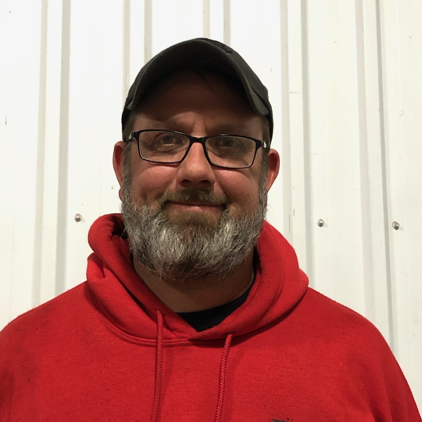 A man in red hoodie wearing glasses and hat.